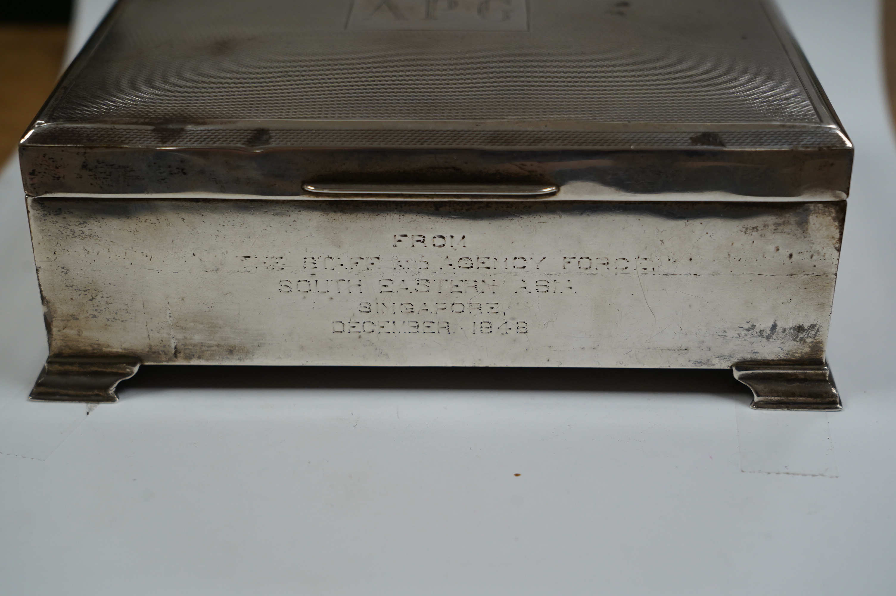 A George VI part engine turned silver cigarette box, Birmingham, 1948, with engraved inscription, on bracket feet, 17.3cm. Condition - poor